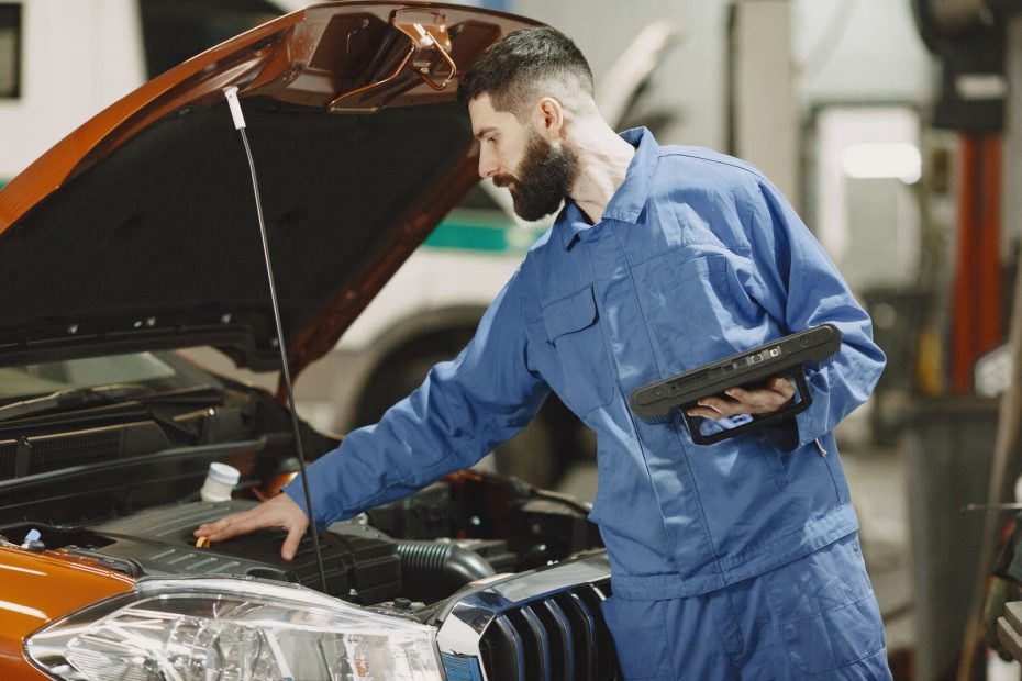 Mecânico usando tablet para verificar o motor de um carro na oficina